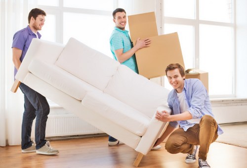 Professional movers carrying furniture through a London residential street